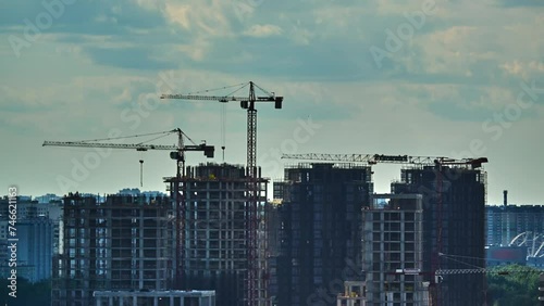 Hyperlapse real estate construction multistory buildings cranes move clouds glides at sky City development real estate construction. Cityscape transforms with new buildings real estate construction.