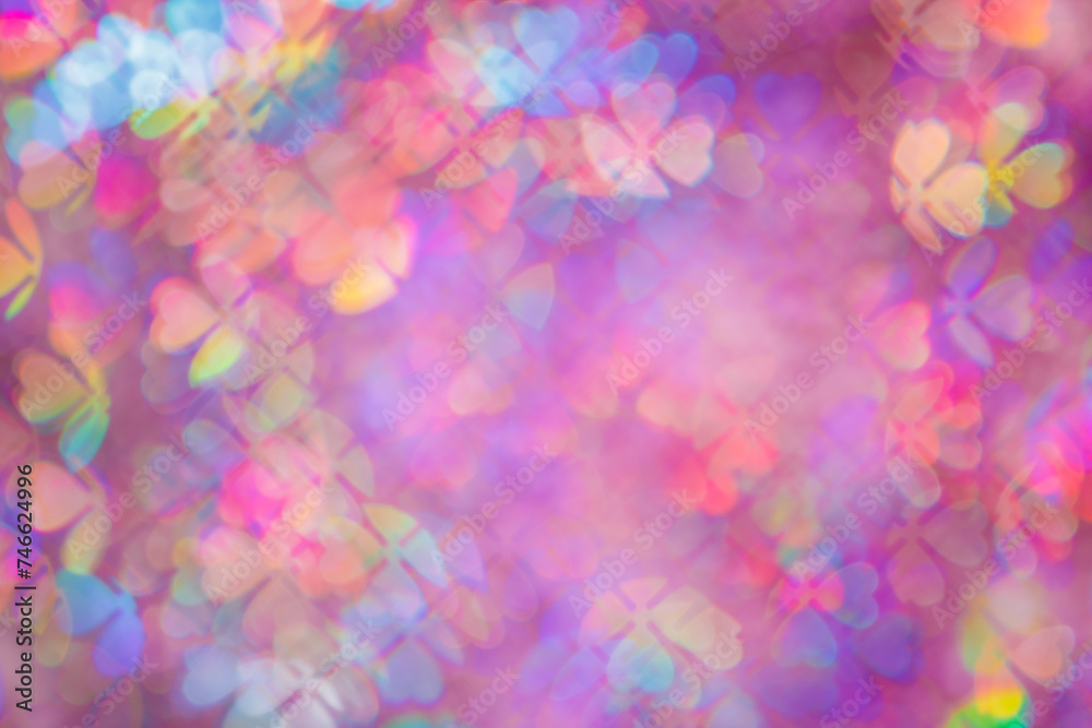 Defocused abstract floral bokeh background purple color, flare from lights, blurred bokeh of clover leaves shape as holiday texture. Colorful festive aesthetic textured lighting pattern
