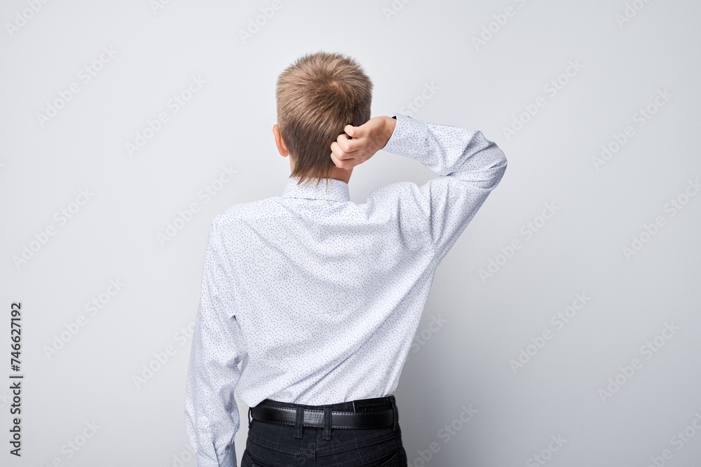 Pensive boy in white shirt scratching his head, puzzled or thinking, isolated on a grey background. Pensive boy in white shirt scratching his head, puzzled or thinking, isolated on a grey background.