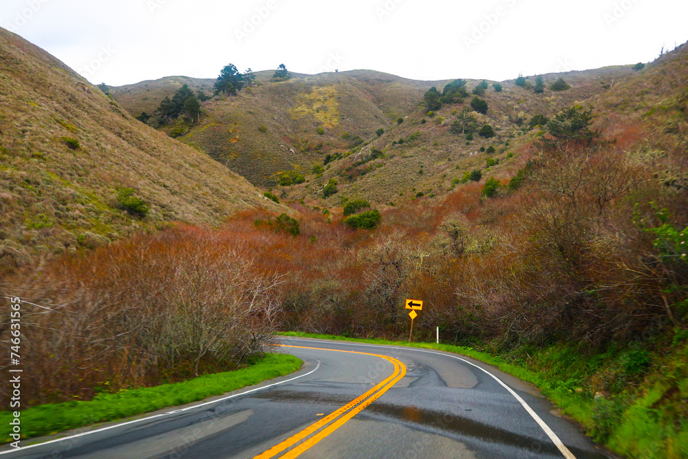 A mountain road winds through breathtaking scenery with beautiful landscapes focused on road signs. Country road with mountains in the background. Road travel filled with adventure.