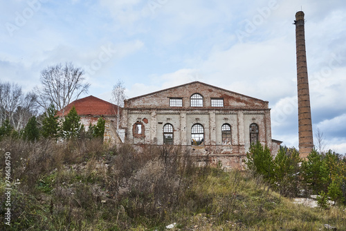 Abandoned destroyed brick building with high chimney. Old facility industrial premises, Glass Factory area overgrown with trees, Krasnoyarsk, Memory 13 Bortsov