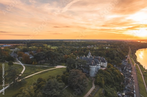 Fototapeta Naklejka Na Ścianę i Meble -  A breathtaking aerial view showcases a magnificent castle nestled amidst a dense forest, surrounded by a sea of verdant trees creating a picturesque scene of tranquility and grandeur.
