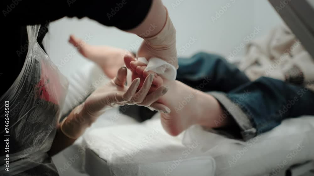 A pedicure master does cleaning and massage, pedicure, to a young beautiful girl with a small foot. Caring for female beauty in a beauty salon during a procedure. Skin of feet and toes close-up A pedicure master does cleaning and massage, pedicure, to a young beautiful girl with a small foot. Caring for female beauty in a beauty salon during a procedure. Skin of feet and toes close-up