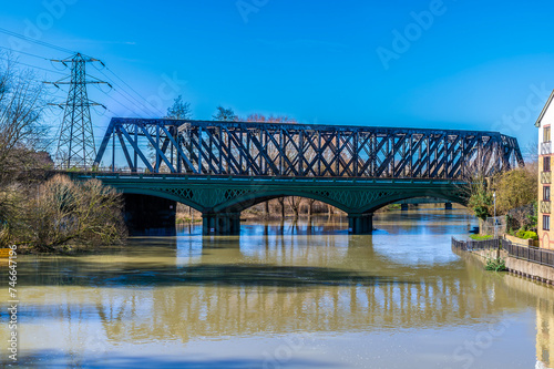 A close up view towards the historic cast iron railway bridge over the River Nene in Peterborough, UK on a bright sunny day