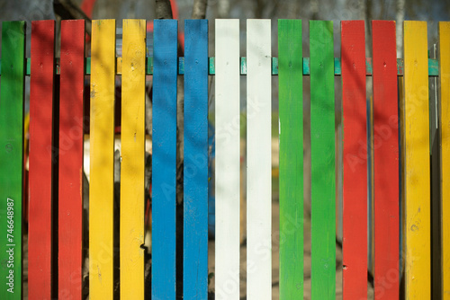 Cheerful fence made of colored boards. Fence in park. Creative design solution.