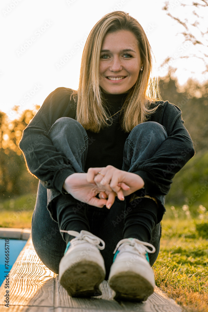 Obraz premium Young woman with short blonde hair sitting on the floor in casual clothes and smiling at the camera