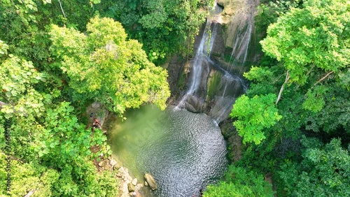 Overhead, descending shot of a tropical, Puerto Rican waterfall, with natural pool at the bottom.