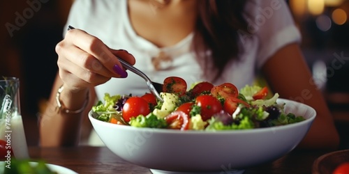 A woman sitting at a table with a bowl of salad. Suitable for healthy eating and lifestyle concepts