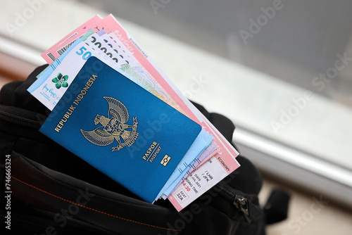 Blue Republic Indonesia passport with money and airline tickets on touristic backpack close up. Tourism and travel concept photo