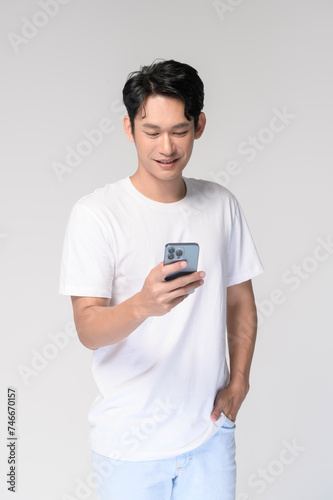 Portrait of young smiling asian man using smartphone over white background © tonefotografia
