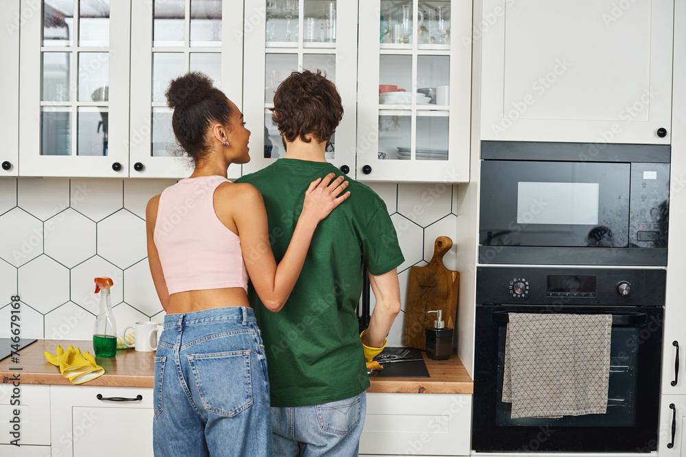 jolly beautiful african american woman looking happily at her loving boyfriend doing his chores jolly beautiful african american woman looking happily at her loving boyfriend doing his chores