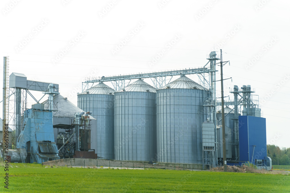 Modern Grain Silos And Storage Buildings On A Rural Farmland During Springtime Modern Grain Silos And Storage Buildings On A Rural Farmland During Springtime