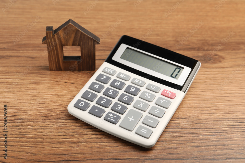 Mortgage concept. House model and calculator on wooden table Mortgage concept. House model and calculator on wooden table