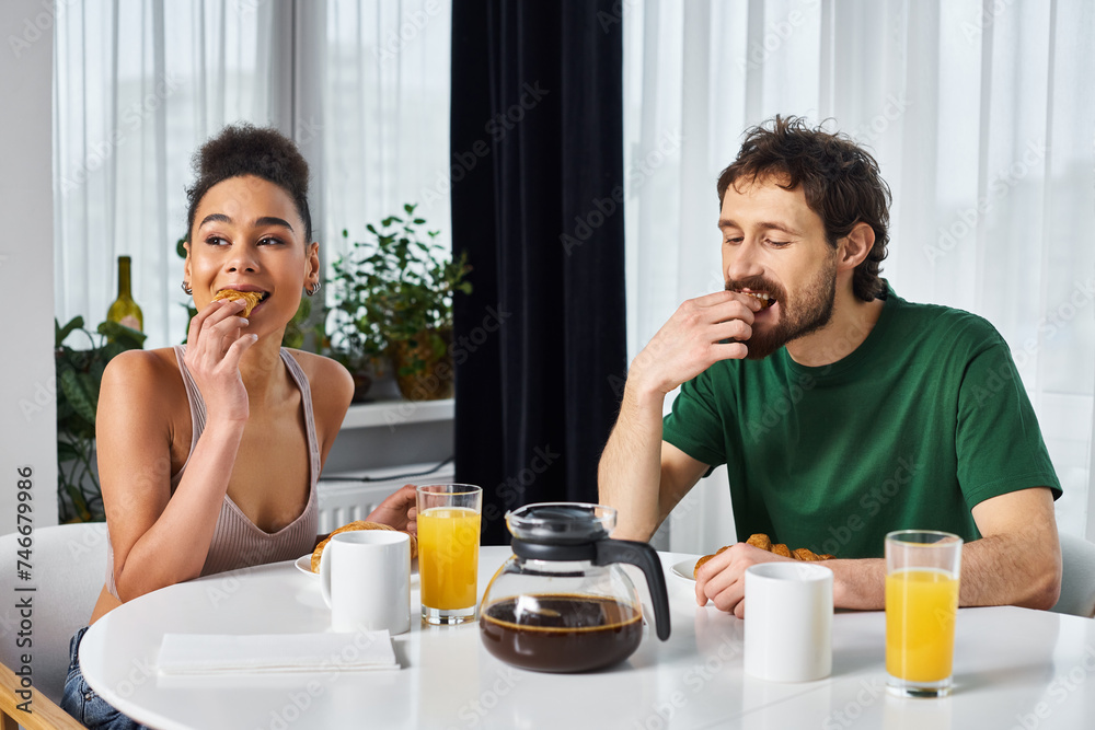 beautiful jolly diverse couple in homewear enjoying their delicious breakfast while at home beautiful jolly diverse couple in homewear enjoying their delicious breakfast while at home