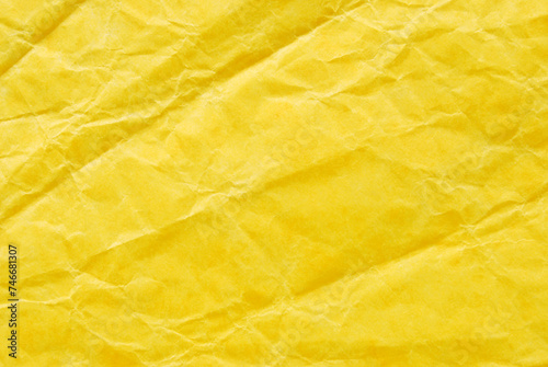 A sheet of wrinkled glossy yellow paper texture as background