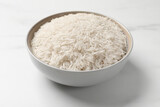 Raw basmati rice in bowl on white marble table
