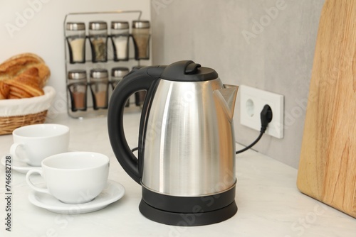 Electric kettle and cups on counter in kitchen