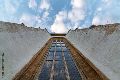 Looking up at a curch facade with a window and cloudy sky photo