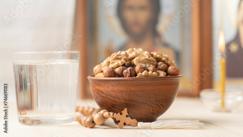 Various nuts in clay cup on table in front of Orthodox icon. Food for Christians during Lent, Lenten foods.