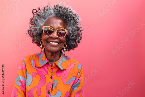 Front view of senior hipster Afro American woman with modern clothes and sunglasses over colorful pink background with copy space photo