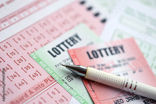 Green and red lottery tickets with pen on blank bills with numbers for playing lottery close up