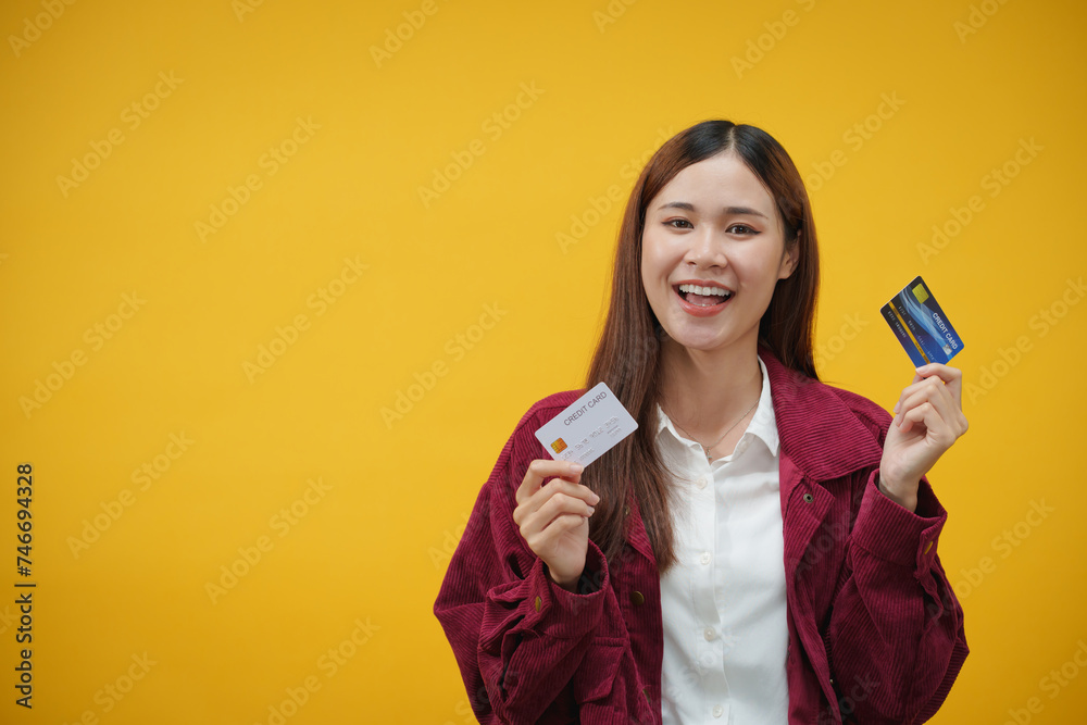 Woman showing credit card for shopping online with happy pleasure isolated over yellow background Woman showing credit card for shopping online with happy pleasure isolated over yellow background