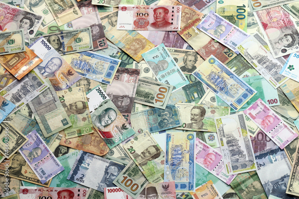 Many banknotes of different currency. Background of big amount of random money bills close up