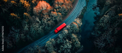 aerial view of large red truck on the road through a green forest. Drone point of view