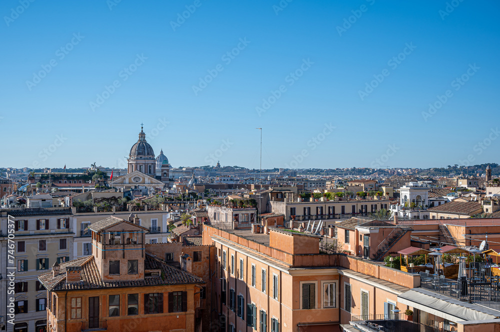 Aerial view of Rome against a blue sky, showcasing the city's majestic skyline. Rooftop bar.