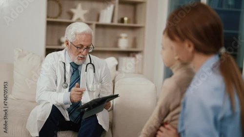 Wallpaper Mural Senior doctor consults family in clinic. Professional pediatrician talking with mom son looking at digital medical card in tablet in modern clinic. Medicine therapist, children appointment checkup. Torontodigital.ca
