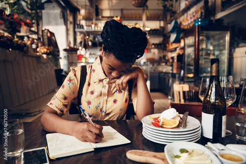 Young waitress doing expenses at a restaurant table photo