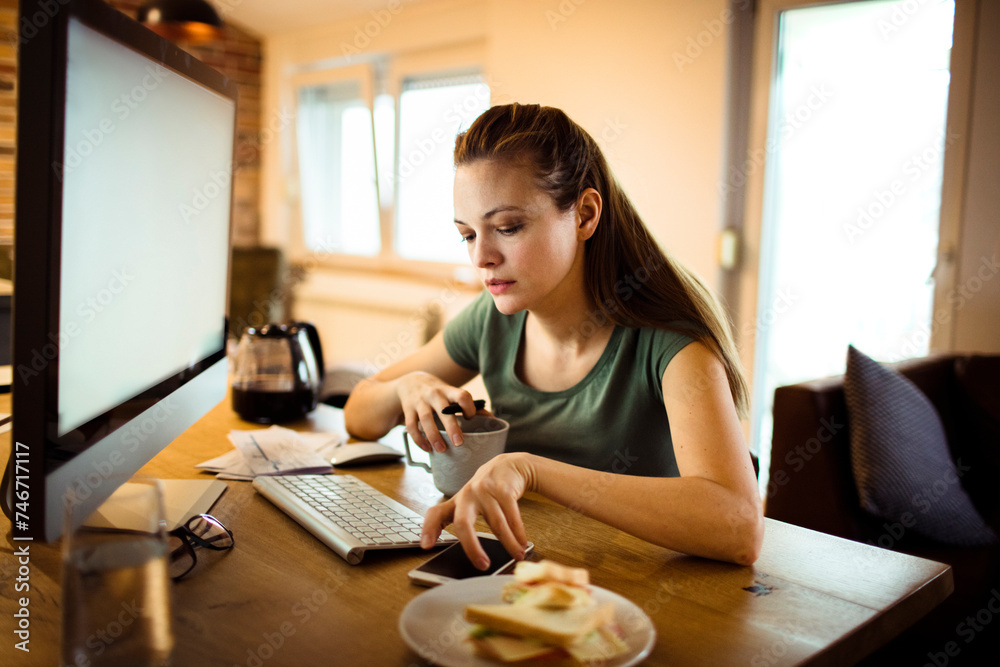 Focused young woman working on computer in home office setting