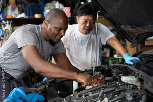 African mechanics or workers checking and fixing a car in garage