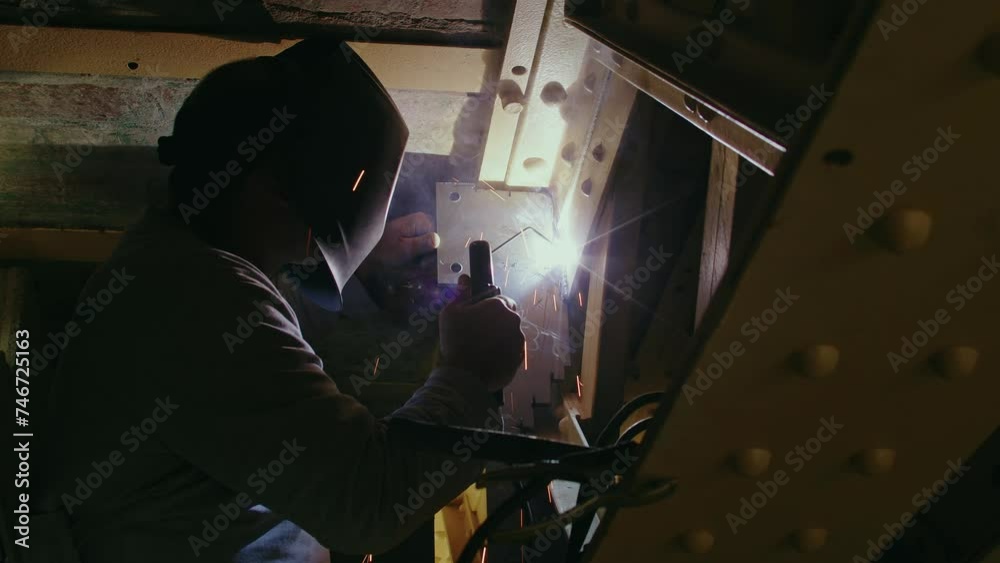 Ouvrier soudant une pièce métallique sur un chantierr industriel Ouvrier soudant une pièce métallique sur un chantierr industriel