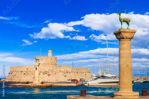 Greece travel, Dodecanese. Rhodes island. entrance of Mandraki Harbor with symbol statue of deer and old lighhouse photo