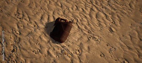 Dirty brown plastic oil container lying in rippled sand of beach.