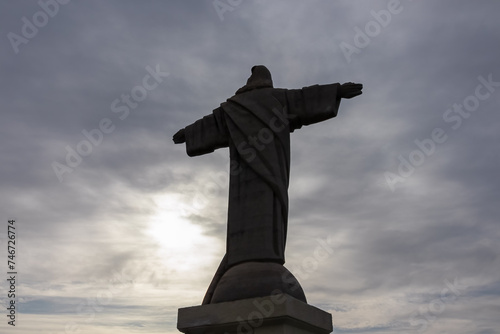 Silhouette of majestic statue of Christ the King statue (Cristo Rei) in Garajau, Madeira island, Portugal, Europe. Landmark against dramatic sky. Serene tranquil atmosphere. Tourist destination photo