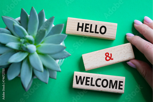 Hello and Welcome symbol. Concept words Hello and Welcome on wooden blocks. Beautiful green background with succulent plant. Businessman hand. Business and Hello and Welcome concept. Copy space. photo