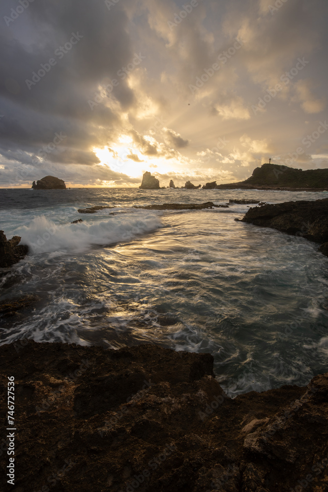 Stony coast with sharp rock formations on a bay in the sea. rainy sunrise, dramatic mood. Pointe des Chateau overlooking Pointes des colibris on Grande Terre, Guadeloupe, French Antilles, Caribbean