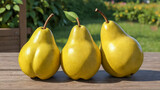 Three ripe yellow pears on wooden table, against blurred background of summer or autumn garden. Fresh natural organic fruits. Healthy vitamin food. Harvesting. Copy space.