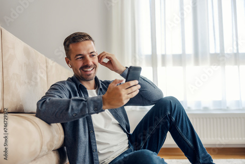 A man is having conference call on the phone while sitting on the floor at home. photo