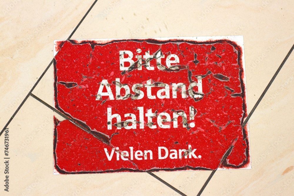 Dank Sign Foto de Worn-out red sign on tiled floor in German: Bitte Abstand ...