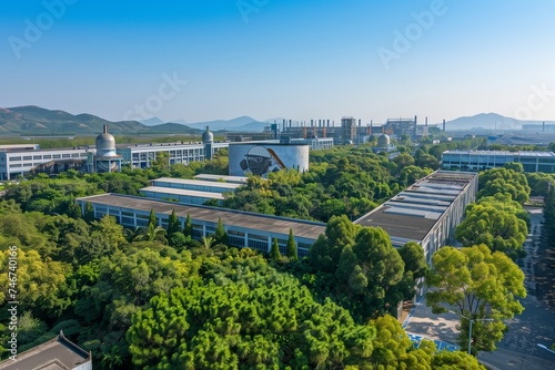 An aerial view of a sprawling factory complex, surrounded by lush greenery, under the clear blue sky of International Labour Day.