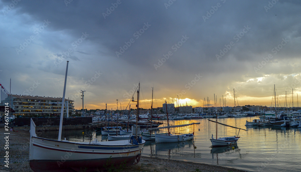 Sunset on the beach with fishing boats and cloudy sky