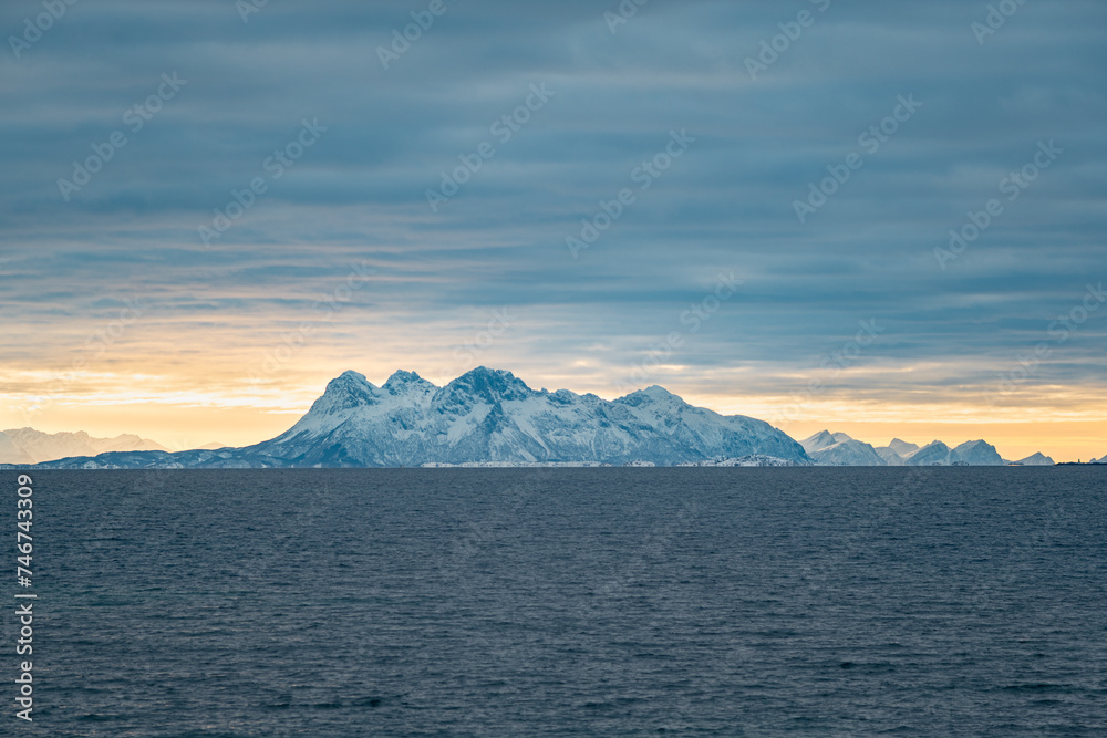 Beautiful view of a mountain range that seems to rise from the waters of the Vestfjorden in northern Norway. Stunning dramatic cloud cover above the mountains.