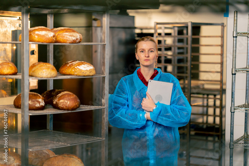 in a professional kitchen a young woman in a blue robe creates a report on production and quality