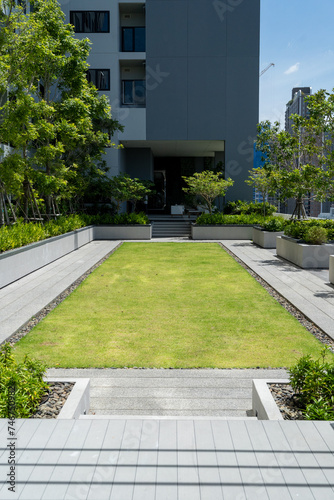 Architectural view of a modern apartment entrance with a neatly landscaped green lawn and pathway.