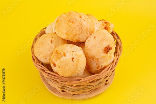 Brazilian cheese bread isolated inside a wooden basket in yellow background in front view