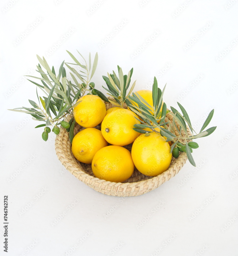 Woven basket with lemons, olive branches on white background, mediterranean diet, spanish greece, italian food