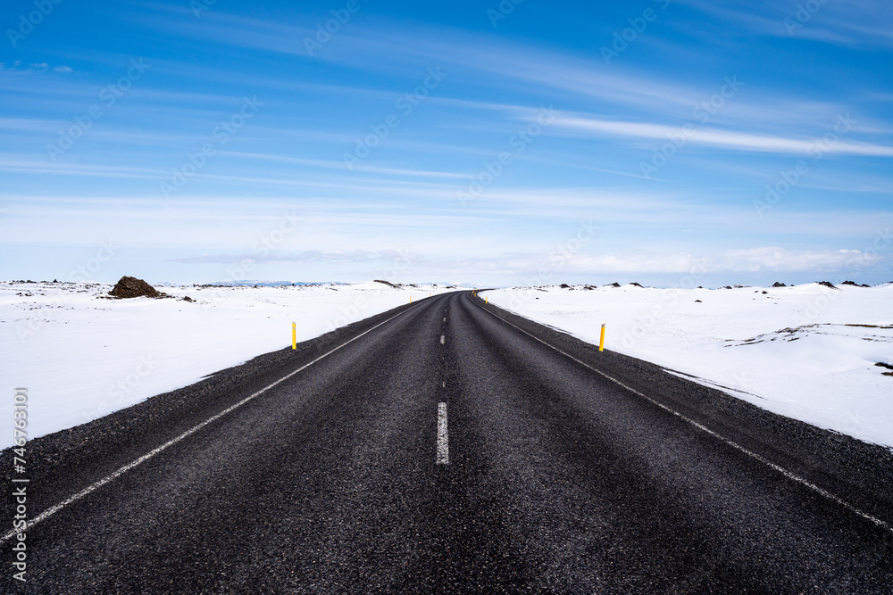 Lonely black asphalt road with snow on the shoulder in Iceland Lonely black asphalt road with snow on the shoulder in Iceland